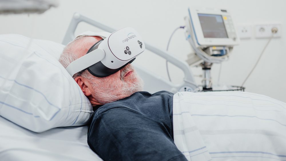 Patient in einem Krankenhausbett trägt eine VR-Brille von Magic Horizons zur Angstbewältigung vor einem medizinischen Eingriff, betreut von einer Ärztin oder Pflegekraft.