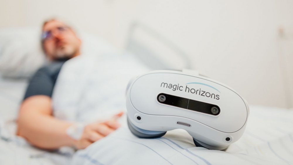 Nahaufnahme einer weißen Magic Horizons Virtual-Reality-Brille auf einem Krankenbett mit Patient im Hintergrund